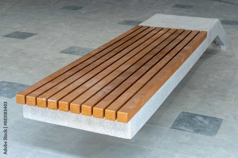 Modern bench with concrete base and wooden seat on a public area Modern bench with concrete base and wooden seat on a public area