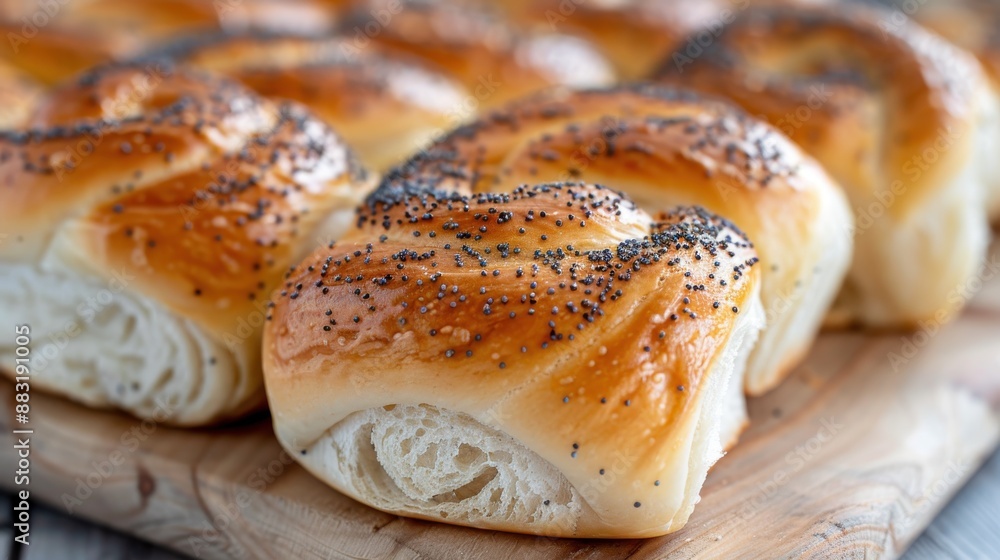 A batch of beautifully baked, golden brown, soft and creamy, poppy seeds rolls, freshly made, placed on a wooden board, ready to be enjoyed with a warm beverage. A batch of beautifully baked, golden brown, soft and creamy, poppy seeds rolls, freshly made, placed on a wooden board, ready to be enjoyed with a warm beverage.