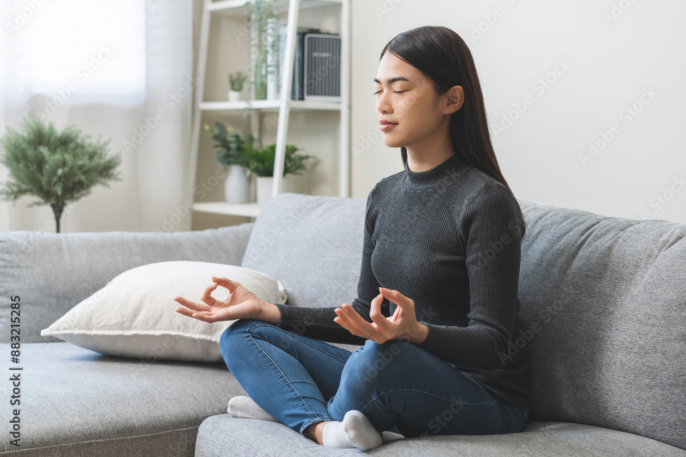 Beautiful asian young woman, girl hands in calm pose sitting practice meditating in lotus position on sofa at home, meditation, exercise for wellbeing, healthy care. Relaxation, happy leisure people. Beautiful asian young woman, girl hands in calm pose sitting practice meditating in lotus position on sofa at home, meditation, exercise for wellbeing, healthy care. Relaxation, happy leisure people.