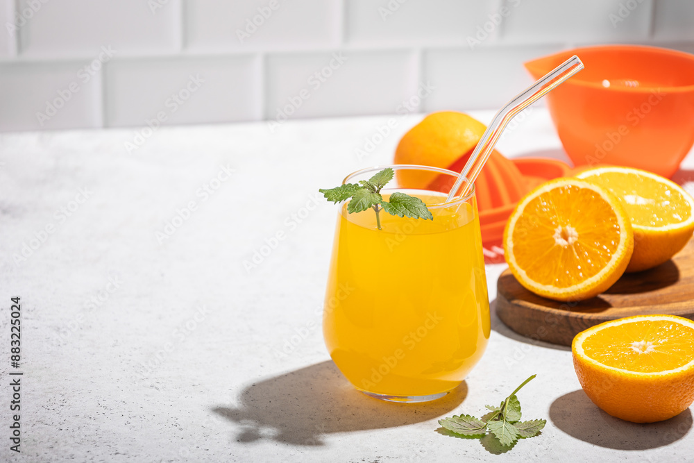 fresh orange juice in a glass with mint and a slice of fruit on the table against a white brick wall. Copy space fresh orange juice in a glass with mint and a slice of fruit on the table against a white brick wall. Copy space