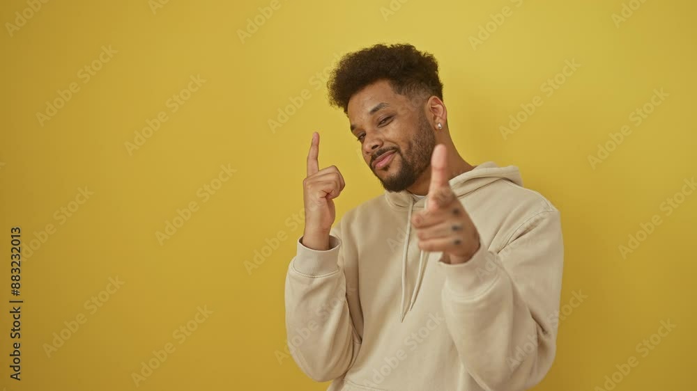 Cheerful african american man, pointing fingers at you, exudes joyful vibes! rocking a trendy yellow hoodie, showing a great smile, standing isolated on yellow. Cheerful african american man, pointing fingers at you, exudes joyful vibes! rocking a trendy yellow hoodie, showing a great smile, standing isolated on yellow.