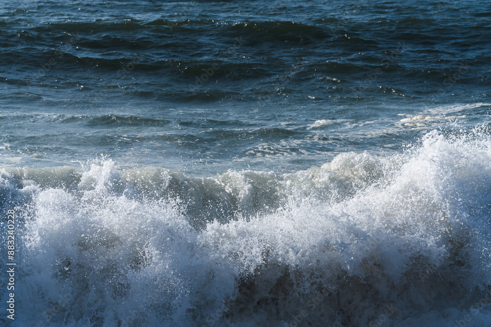 Foaming white ocean waves at the shore close-up, blue water in the background. Foaming white ocean waves at the shore close-up, blue water in the background.