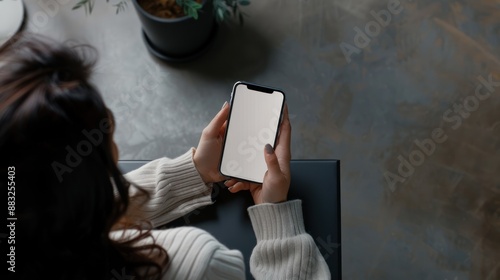 a woman sits her hand holding a cell phone