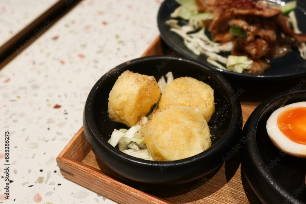 close up of Japanese style seasoned deep fried braised egg tofu in a black bowl close up of Japanese style seasoned deep fried braised egg tofu in a black bowl