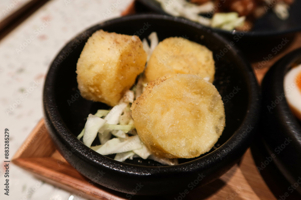 close up of Japanese style seasoned deep fried braised egg tofu in a black bowl close up of Japanese style seasoned deep fried braised egg tofu in a black bowl