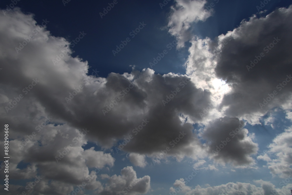 Cielo azul con nubes tipo cúmulos a contraluz, ocultando parcialmente el sol. Cielo azul con nubes tipo cúmulos a contraluz, ocultando parcialmente el sol.