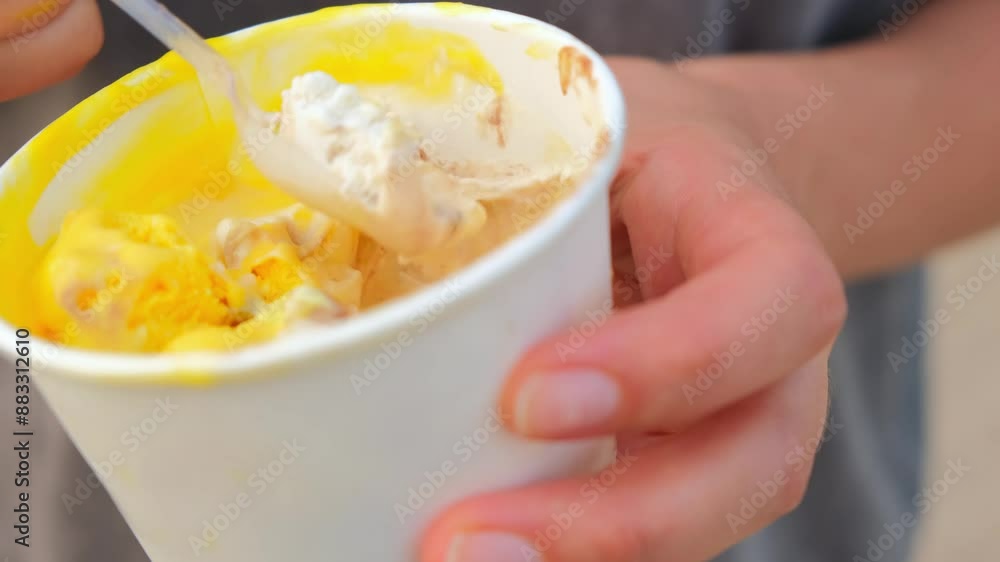 A woman's hand picks up ice cream balls with a spoon. The girl is eating ice cream A woman's hand picks up ice cream balls with a spoon. The girl is eating ice cream
