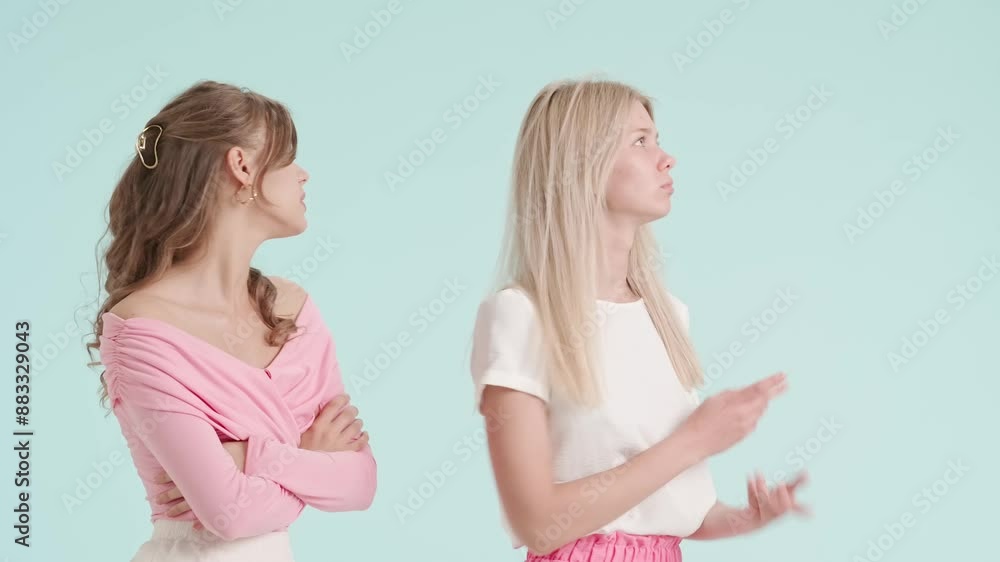 Young fashionable women models talking arguing and quarrelling, negative expression, isolated on blue background. Fashion and youth beauty concept. Young fashionable women models talking arguing and quarrelling, negative expression, isolated on blue background. Fashion and youth beauty concept.