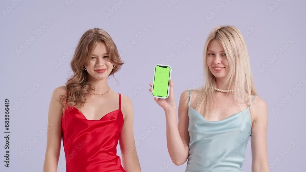 Young stylish women models holding smartphone chroma key green screen and pointing, isolated on purple background. Fashion and youth beauty concept. Young stylish women models holding smartphone chroma key green screen and pointing, isolated on purple background. Fashion and youth beauty concept.