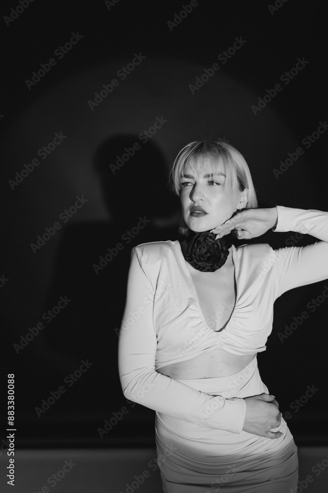 Black and white portrait of an elegant woman with blonde bob haircut and stylish dress posing against a dark background. Copy space. Black and white portrait of an elegant woman with blonde bob haircut and stylish dress posing against a dark background. Copy space.