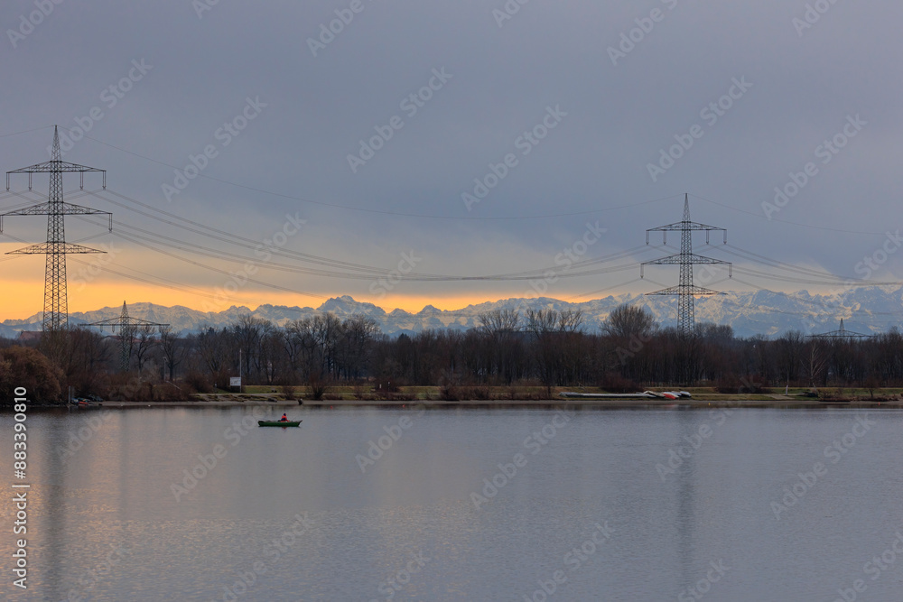 Φωτογραφία A fisherman in a rowing boat on Lake Mandicho near Mering with the Alps in the b