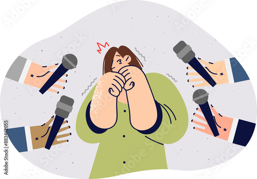 Woman experiences glossophobia and fear of public speaking, stands among hands of journalists with microphones. Panic attack caused by glossophobia in girl answering questions from reporters photo