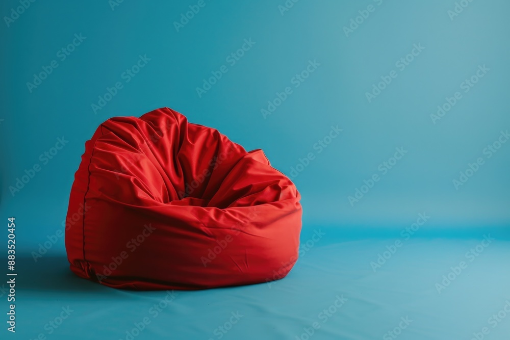 A red bean bag sits atop a blue floor, offering a cozy seating option A red bean bag sits atop a blue floor, offering a cozy seating option