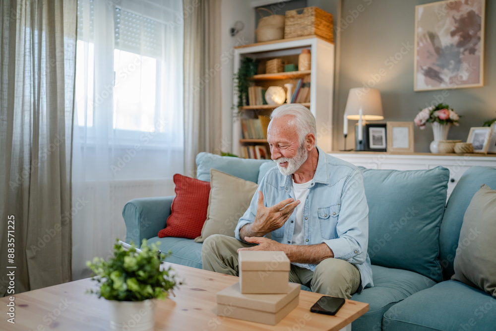 one senior man open box presents and read card while on video call one senior man open box presents and read card while on video call