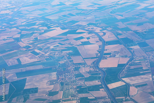 Aerial view of patchwork of green and brown fields near river
