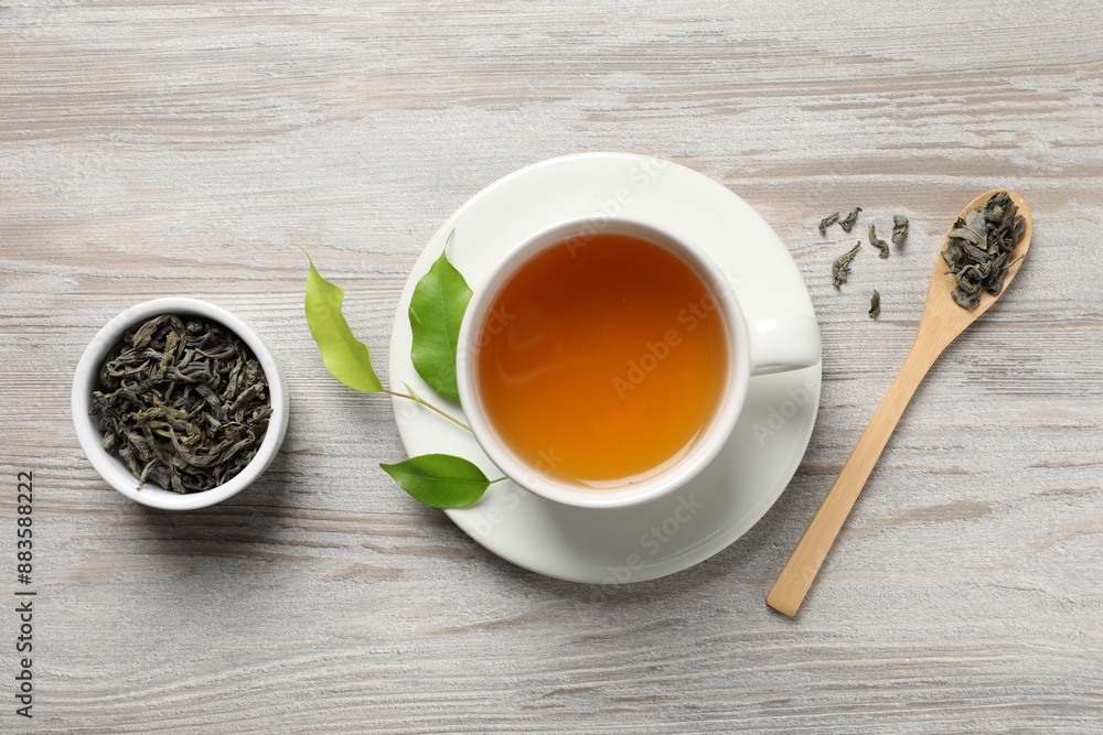 Refreshing green tea in cup, spoon and leaves on light wooden table, flat lay Refreshing green tea in cup, spoon and leaves on light wooden table, flat lay