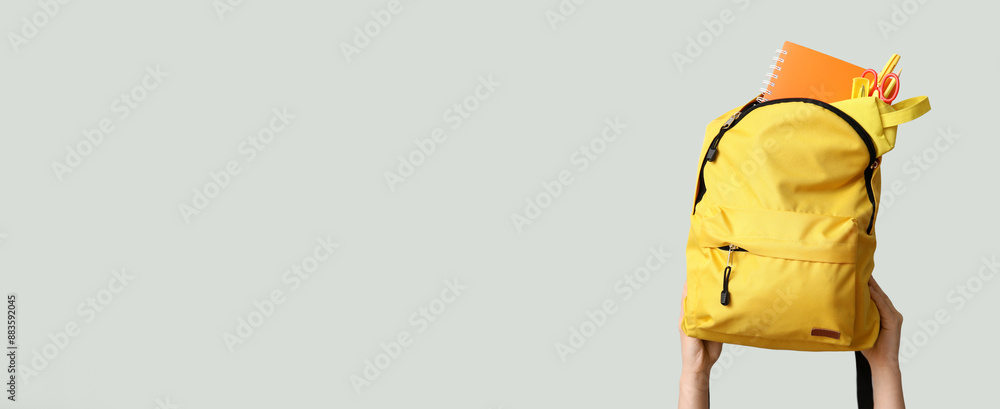 Hands holding school backpack on grey background with space for text Hands holding school backpack on grey background with space for text