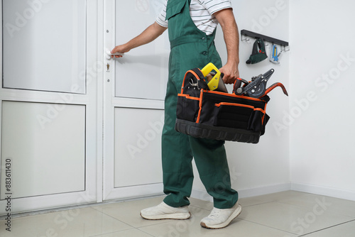 Male worker with tool bag near door in office