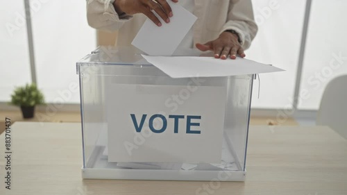 An african american man casting a vote in an electoral ballot box in an indoor voting room, emphasizing the democratic voting process and the importance of civic engagement.