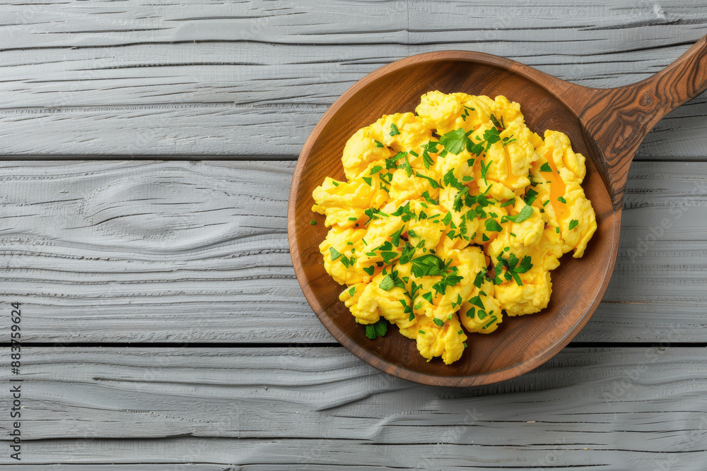 Top view of delicious scrambled eggs with chives on wooden table.
