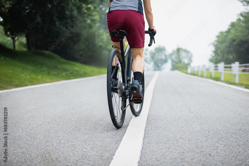 Woman cycling on summer park trail Woman cycling on summer park trail