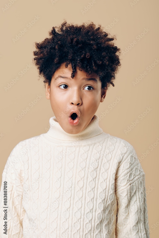 Astonished african american child in white sweater with mouth agape, expressing unbridled surprise and wonderment Astonished african american child in white sweater with mouth agape, expressing unbridled surprise and wonderment