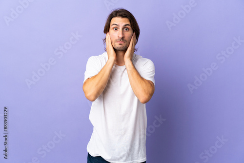 Young handsome man isolated on purple background frustrated and covering ears photo