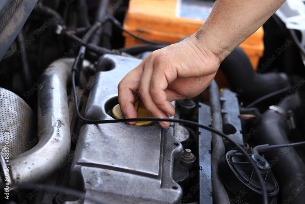 Change of oil. A man's hand opens or closes the oil filler cap. Changing the oil in a diesel car engine. Car maintenance. Old car. The mechanic inspects the car Change of oil. A man's hand opens or closes the oil filler cap. Changing the oil in a diesel car engine. Car maintenance. Old car. The mechanic inspects the car