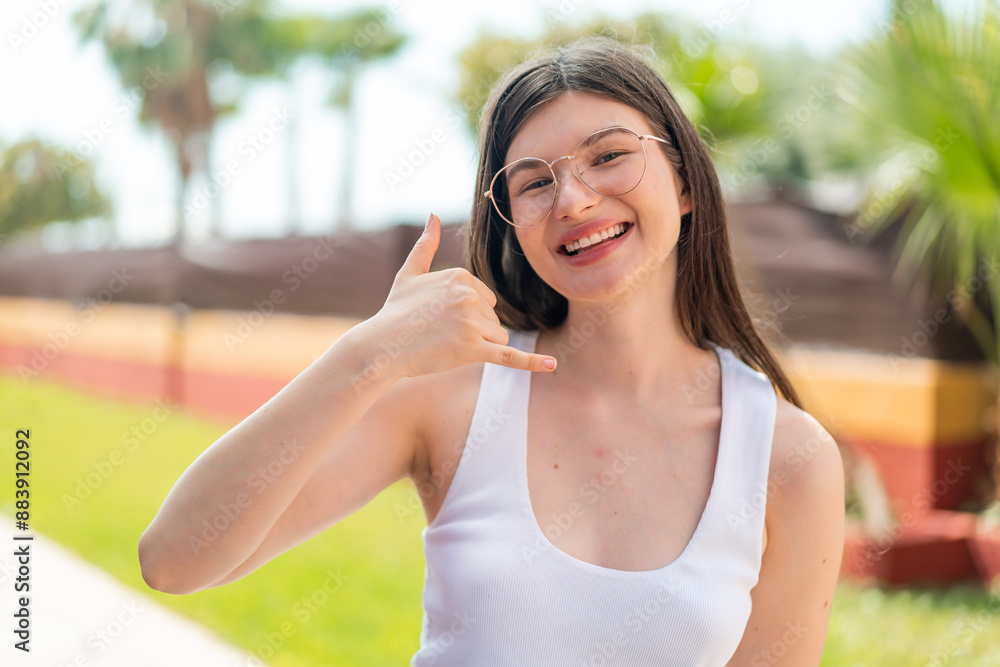 Young pretty woman at outdoors With glasses and doing phone gesture Young pretty woman at outdoors With glasses and doing phone gesture