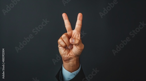 Business hand showing a peace sign against dark background, negotiation success