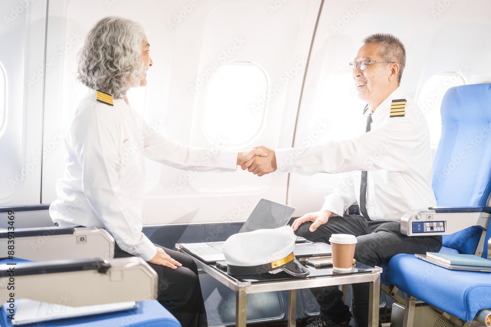 Mature male and female pilots meet inside an airplane, holding hands. Their gesture signifies teamwork, trust, and camaraderie in aviation, fostering a safe and collaborative work environment. Mature male and female pilots meet inside an airplane, holding hands. Their gesture signifies teamwork, trust, and camaraderie in aviation, fostering a safe and collaborative work environment.