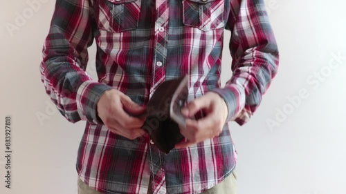 resigned man shows wallet and it is empty, he's wearing a checkered shirt and he stays on a white background
