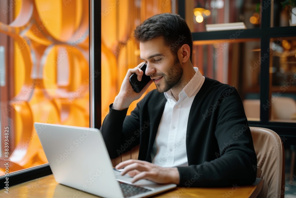 POrtrait of a handsome businessman sitting in the cafe and talking on the phone while working on his laptop POrtrait of a handsome businessman sitting in the cafe and talking on the phone while working on his laptop