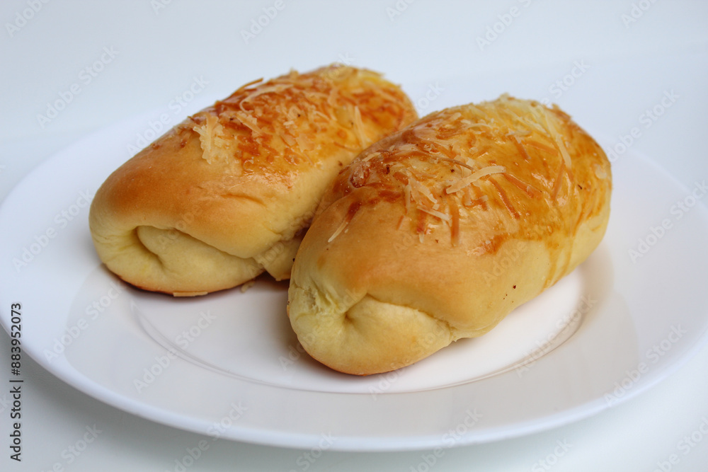 Two baked bread with grated cheese on top, on white plate, isolated on white background Two baked bread with grated cheese on top, on white plate, isolated on white background