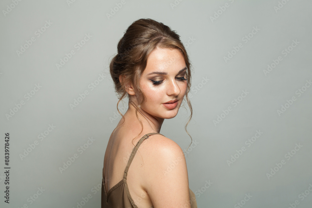 Fashionable glam woman fashion model with makeup and updo hairstyle on gray studio background Fashionable glam woman fashion model with makeup and updo hairstyle on gray studio background
