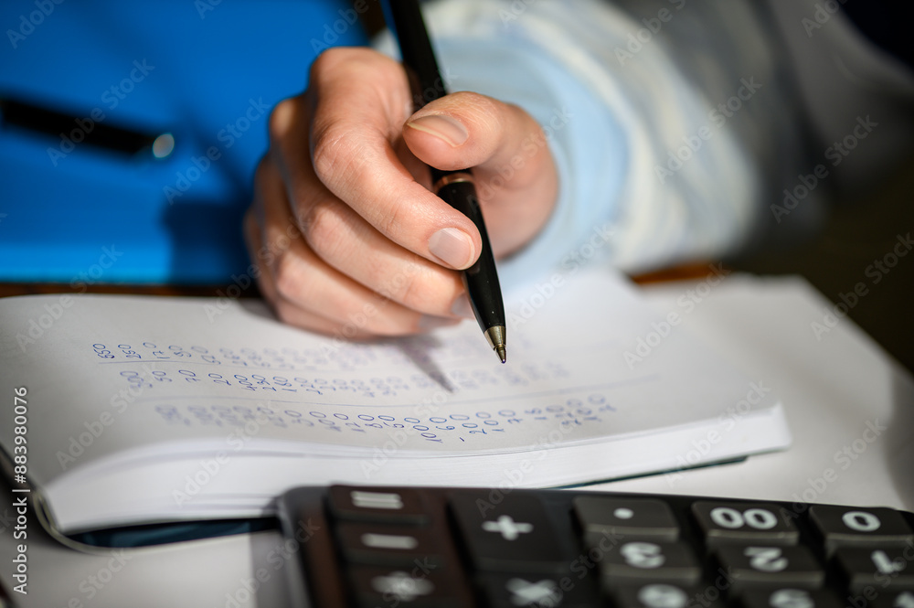 Rozwiązywać przy biurku zadanie matematyczne, kalkulator i zeszyt Rozwiązywać przy biurku zadanie matematyczne, kalkulator i zeszyt
