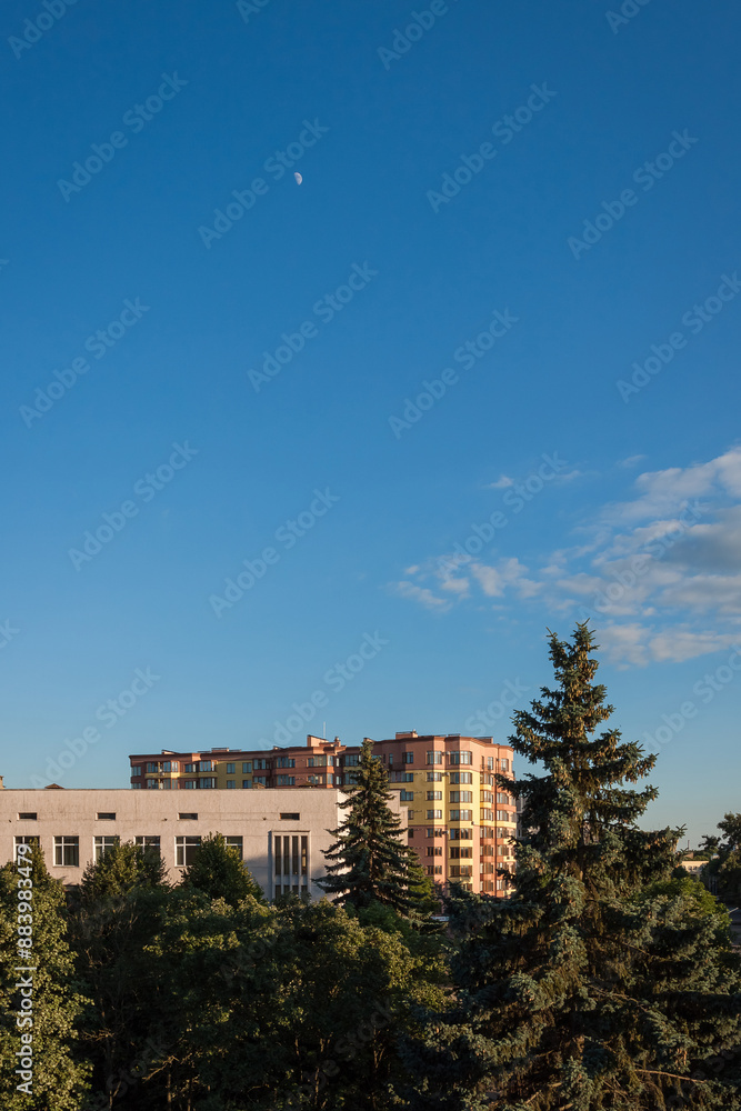 Obraz premium View from the window to the street with high-rise buildings. Houses on the background of the blue sky