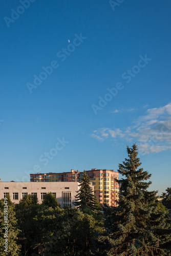 View from the window to the street with high-rise buildings. Houses on the background of the blue sky