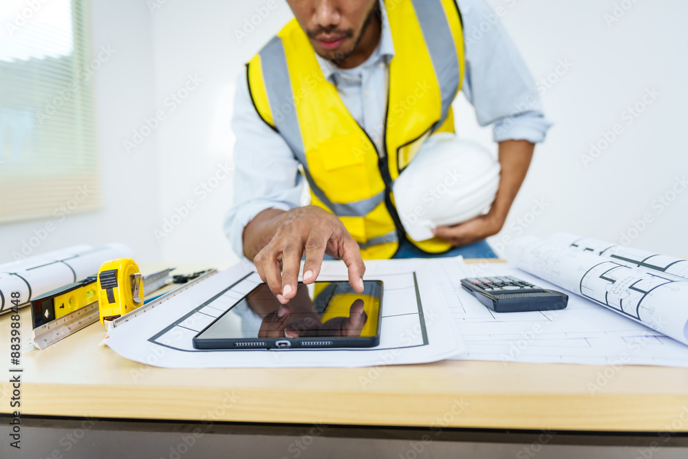 Asian male architect works at desk with house model toy and A3 paper blueprints, construction real estate law, zoning, permits, and resolving property disputes through arbitration and litigation. Asian male architect works at desk with house model toy and A3 paper blueprints, construction real estate law, zoning, permits, and resolving property disputes through arbitration and litigation.