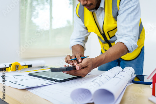 Wallpaper Mural Asian male architect works at desk with house model toy and A3 paper blueprints, construction real estate law, zoning, permits, and resolving property disputes through arbitration and litigation. Torontodigital.ca