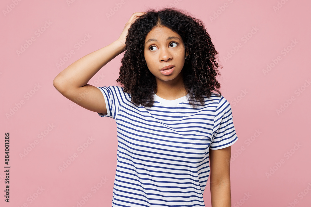 Little sad kid teen girl she wears blue striped t-shirt casual clothes hold scratch head look aside on area isolated on plain pastel light pink background studio portrait. Childhood lifestyle concept. Little sad kid teen girl she wears blue striped t-shirt casual clothes hold scratch head look aside on area isolated on plain pastel light pink background studio portrait. Childhood lifestyle concept.