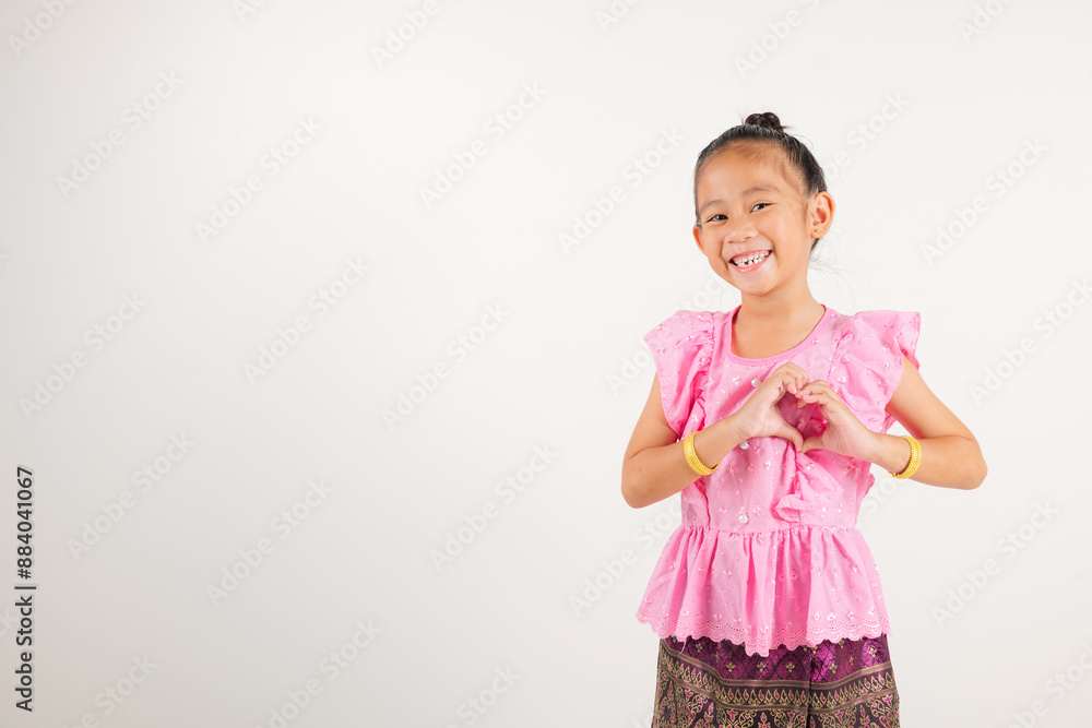 Portrait Thailand kid girl smiling traditional Thai dress costume shows creating heart shape with fingers and hands, studio isolated white background, kindergarten child sending love for Valentine day Portrait Thailand kid girl smiling traditional Thai dress costume shows creating heart shape with fingers and hands, studio isolated white background, kindergarten child sending love for Valentine day