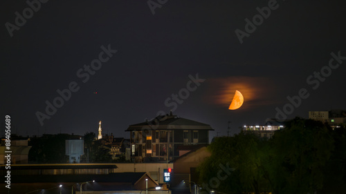 luna rossa di notte con vista della madonnina del duomo di milano photo