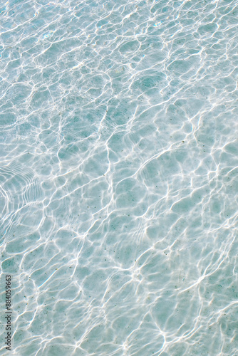 Close-up of clear blue water in a swimming pool reflecting dazzling sunlight