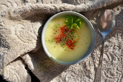 Obraz na plátně grey bowl with white soup sprinkled by red pepper and parsley, top view