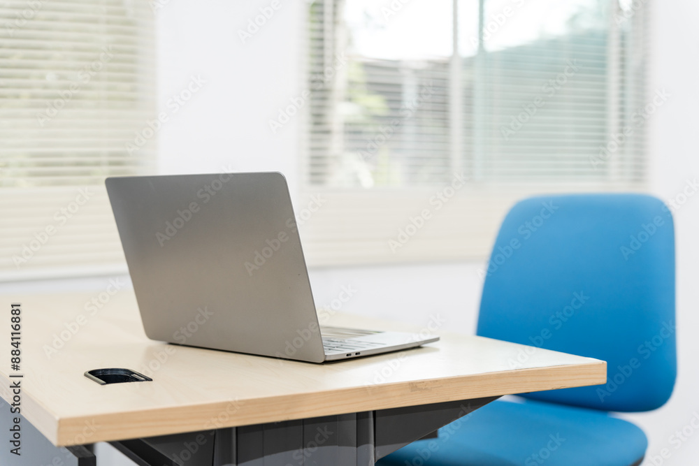 An empty desk in a minimalist office setting, featuring a blank workspace, large windows, a laptop, and a blue office chair against a white wall background, ideal for product montages. no people An empty desk in a minimalist office setting, featuring a blank workspace, large windows, a laptop, and a blue office chair against a white wall background, ideal for product montages. no people