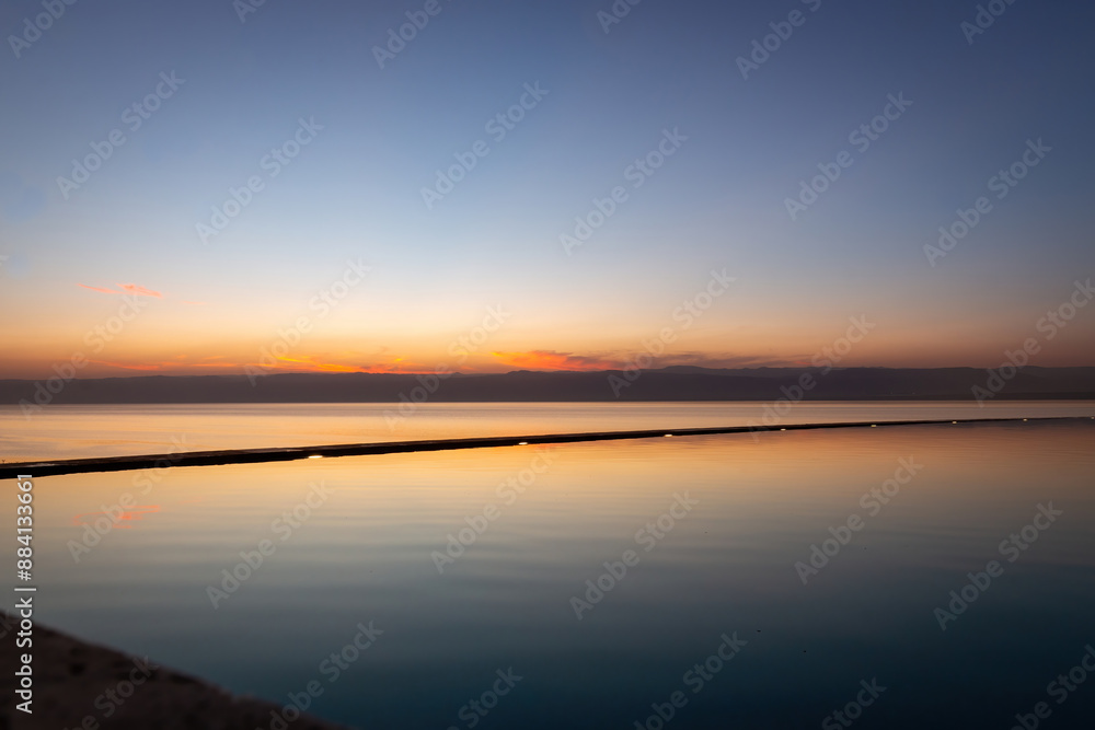 Naklejka premium Sunset at Dead Sea looking form Jordan towards Israel with a swimming pool in the foreground