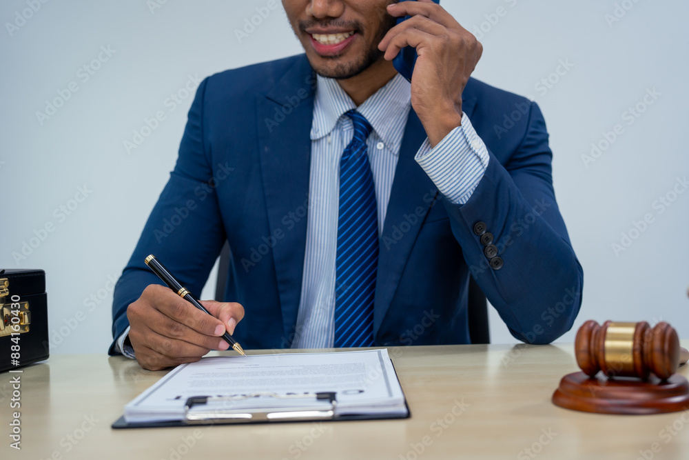 An Asian businessman in a formal suit works alone at a lawyer's desk, by golden scales, law books, leather bags, and a Lady Justice statue, emphasizing personal freedom and legal empowerment.