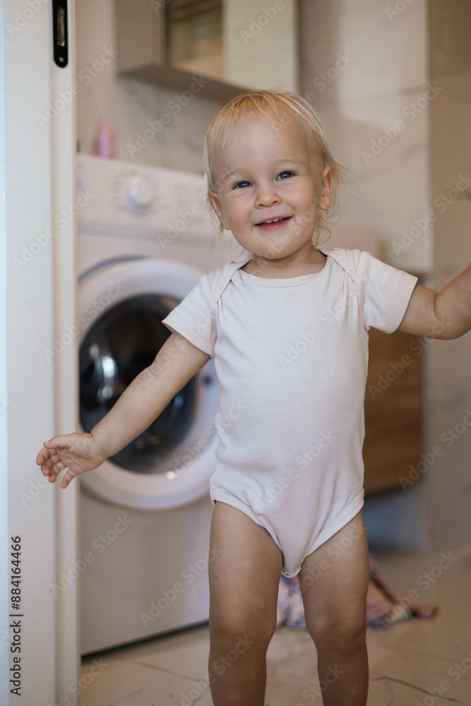 Two year old child doing household chores. Loading washing machine. Two year old child doing household chores. Loading washing machine.