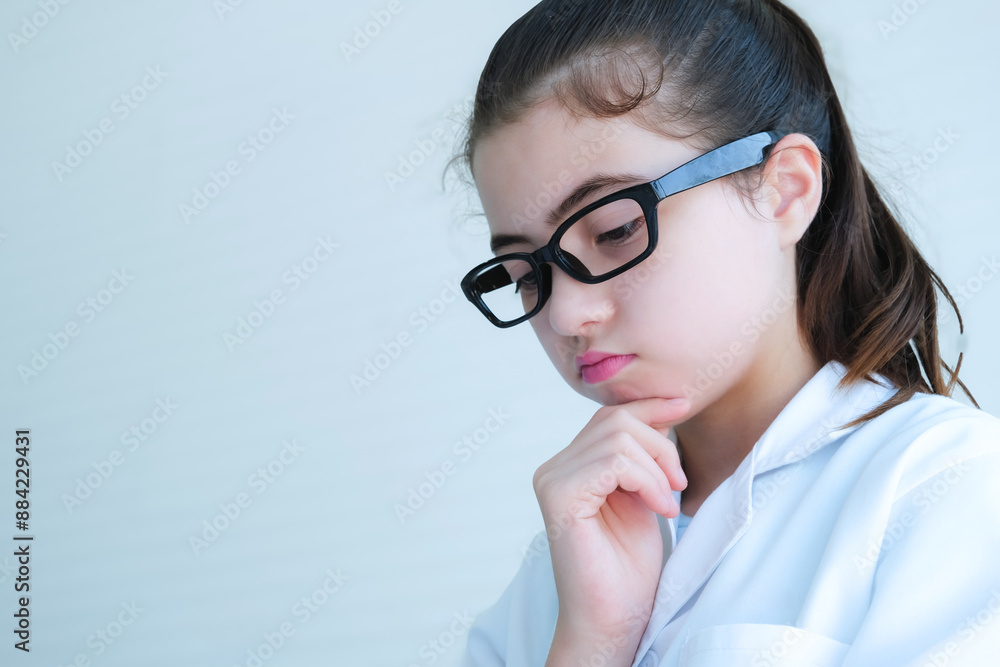 Cute young girl wearing glasses holds her chin in thoughtful pose about results science experiment.